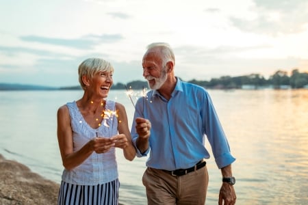 senior couple on beach holding sparkler